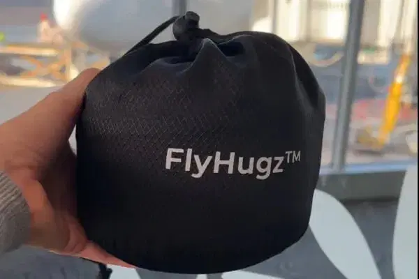 Cream travel neck pillow clipped compactly to a carry-on suitcase